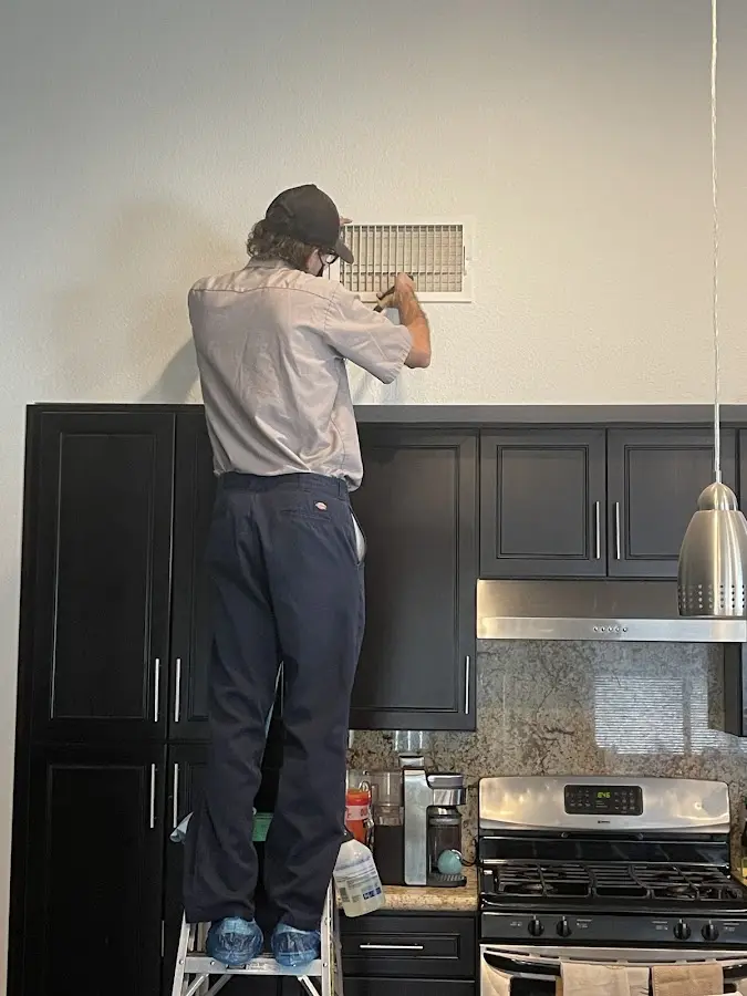 Technician inspecting an air vent during HVAC service in Alvin